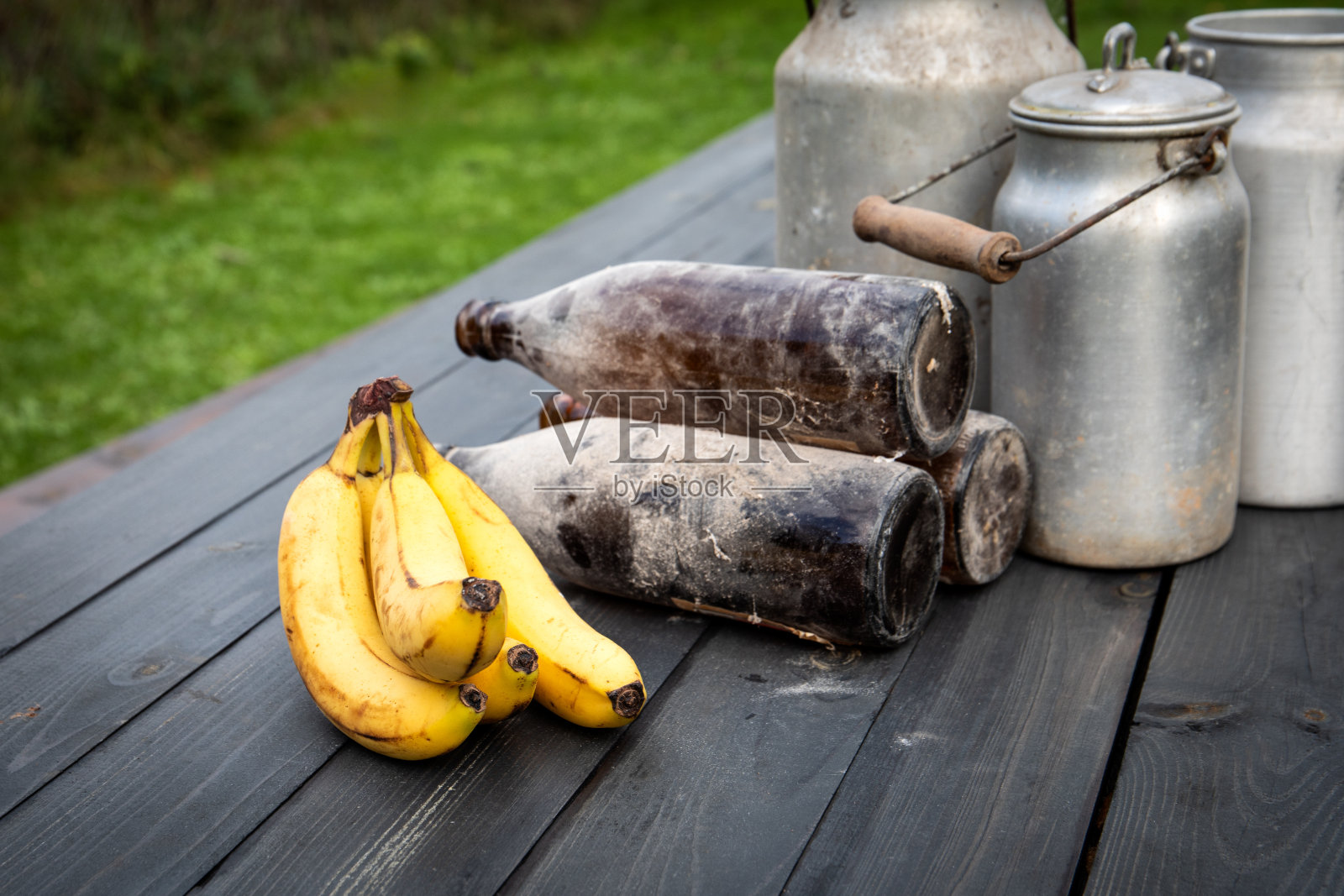 木桌上的香蕉、旧瓶子和金属罐，构成了乡村环境照片摄影图片