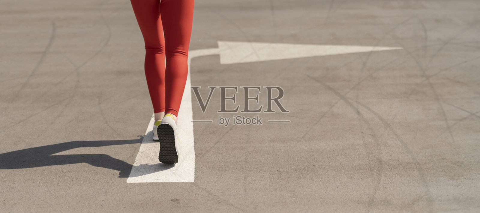 近景，一名女子跑步者的后景，路上画着箭头照片摄影图片