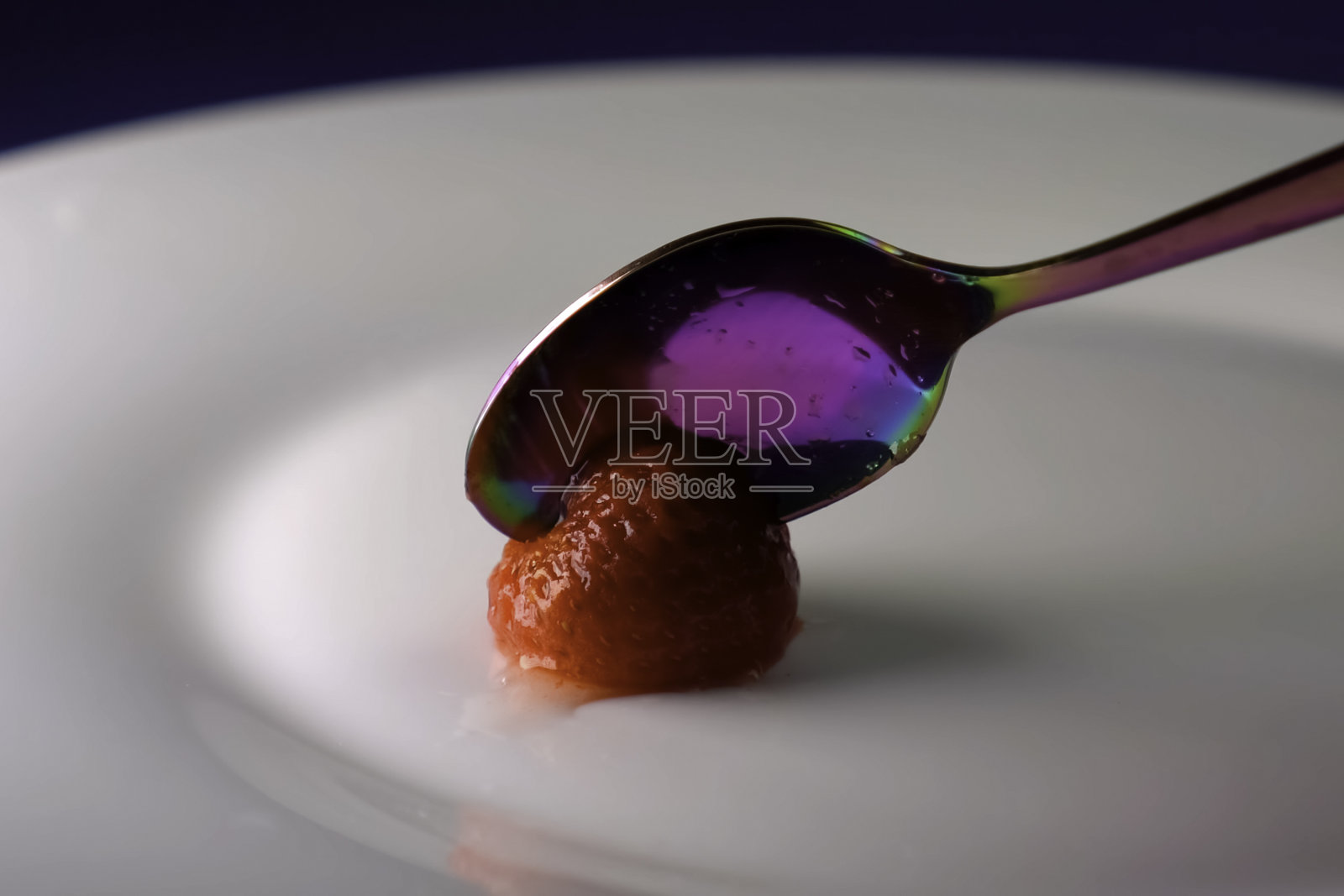 草莓用茶匙分开。盘子里的草莓照片摄影图片