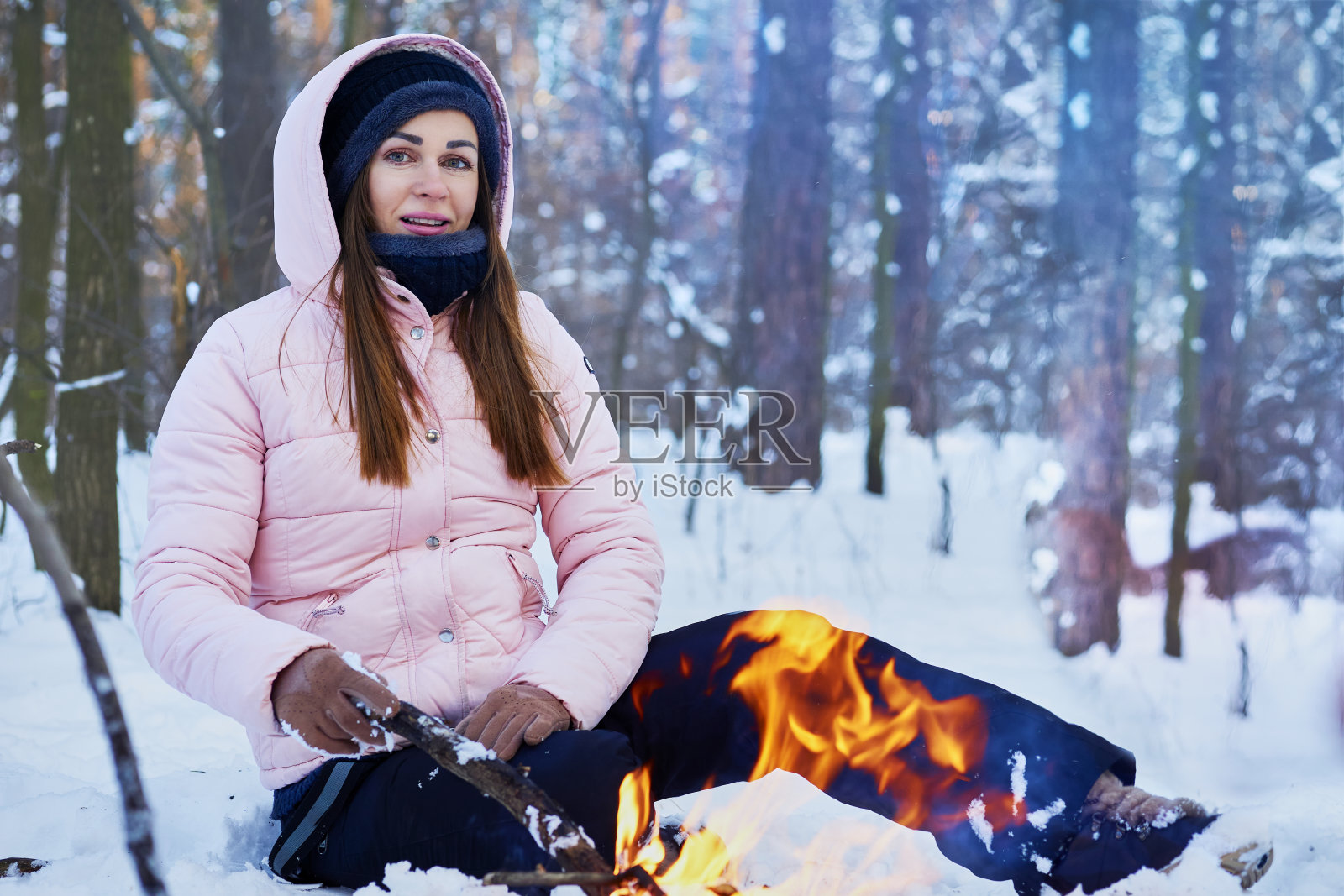 一位年轻女子在森林里冬日野餐，在火堆旁取暖照片摄影图片