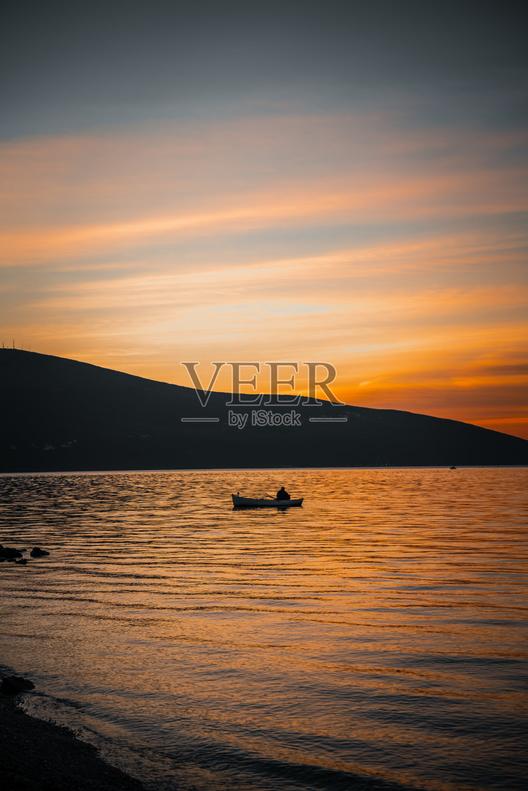 在黑山的亚得里亚海，一名男子在船上捕鱼照片摄影图片