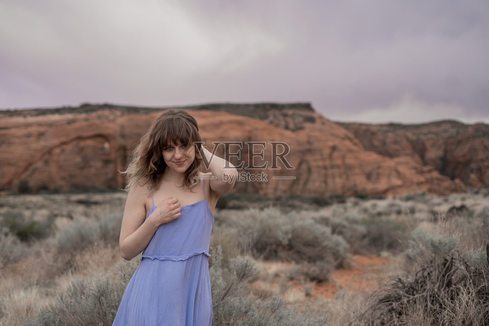 在沙漠岩石区，宁静色的薄带子裙子长出了金色的刘海照片摄影图片