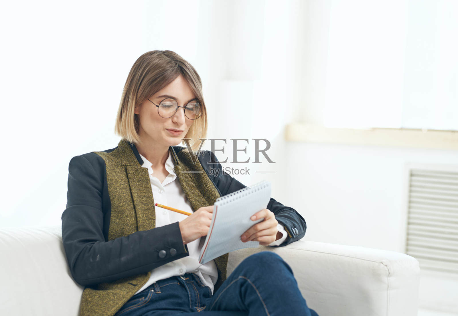 办公室女模特坐在沙发上，手里拿着文件照片摄影图片