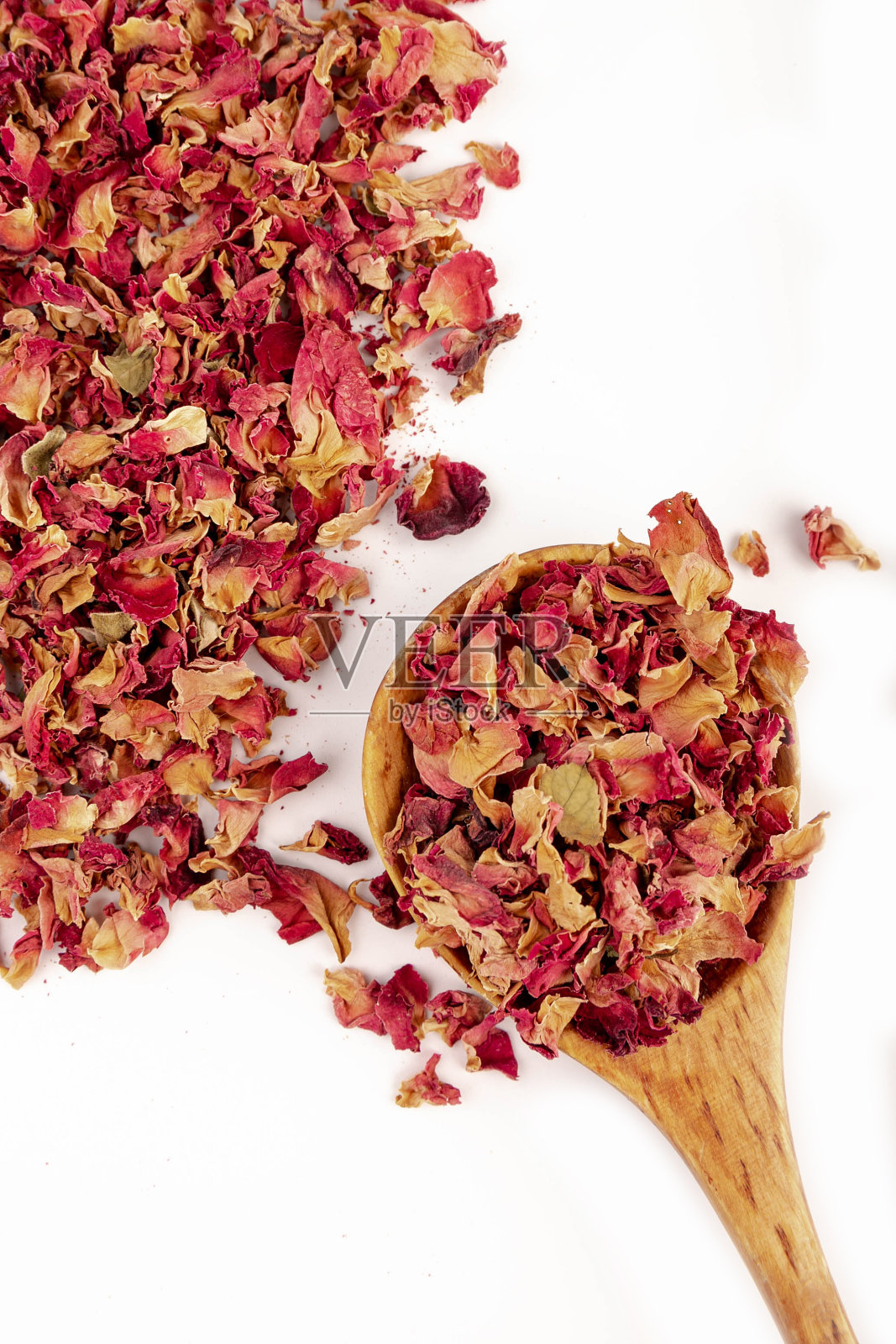 用玫瑰花瓣装在木勺里制成的白底茶。照片摄影图片