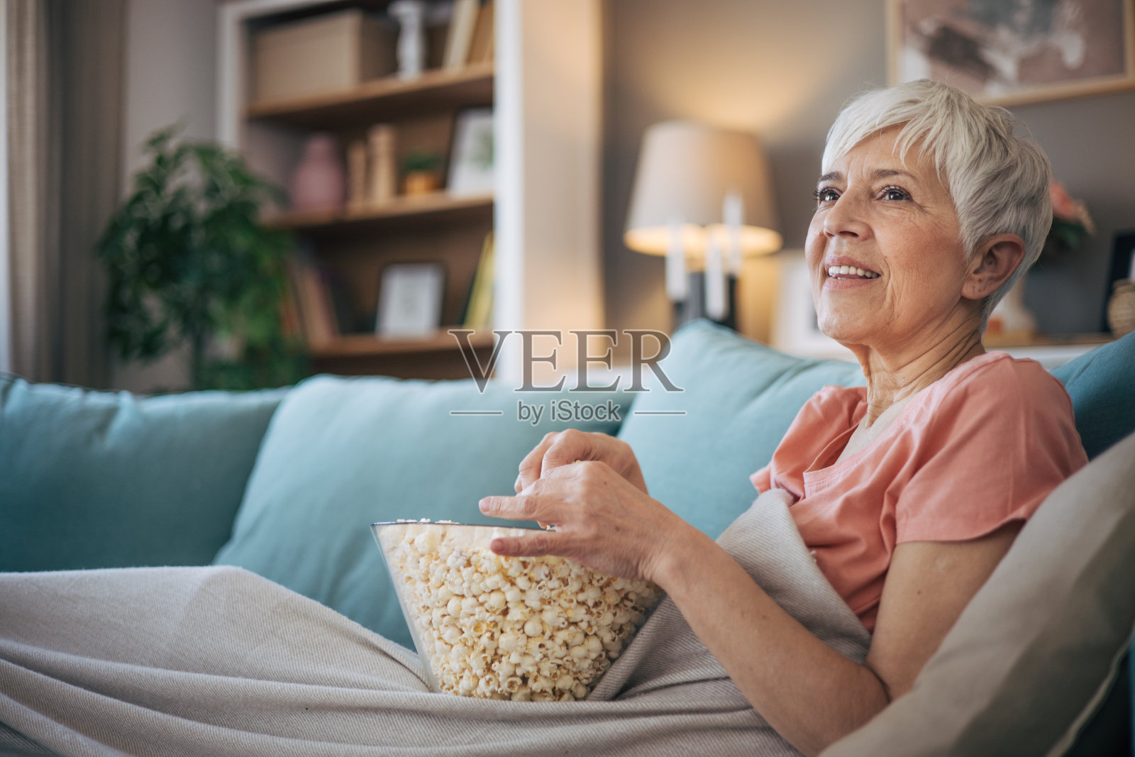 老女人一边看电视一边吃爆米花照片摄影图片