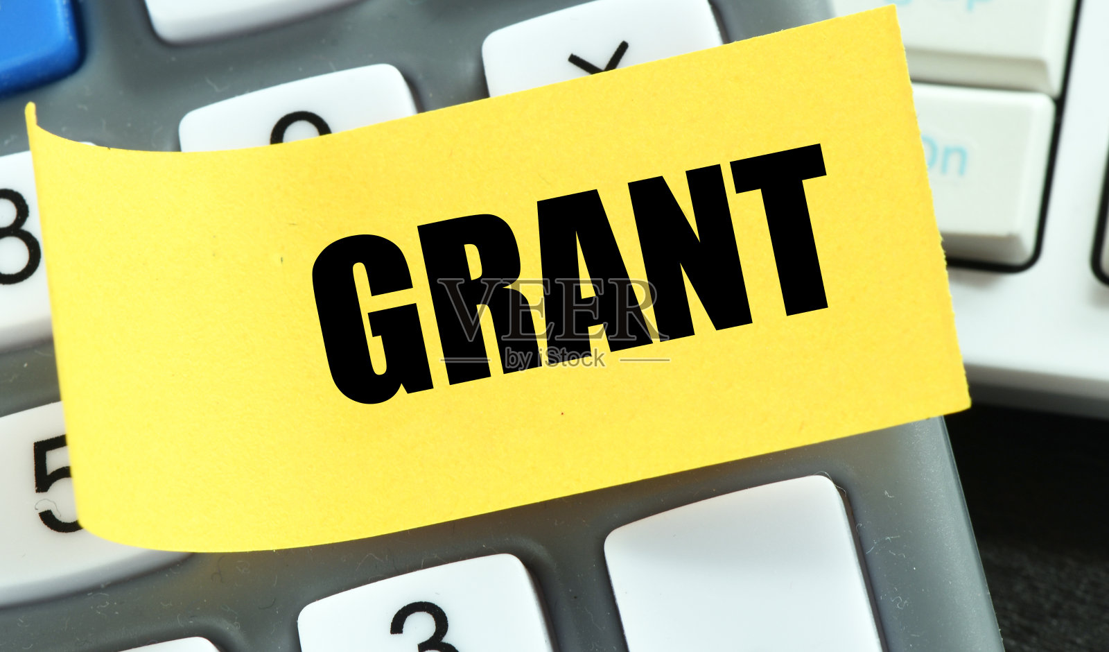 GRANT这个词写在一张黄色的纸和一个计算器上。照片摄影图片