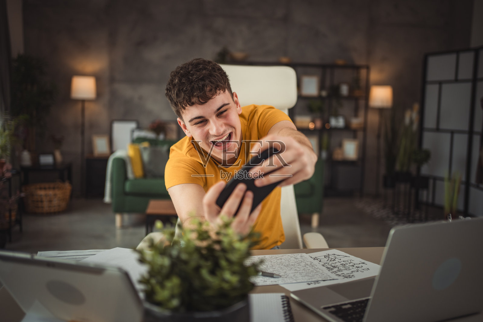 青少年从学习中休息一下，坐在办公桌前玩手机玩视频游戏或上网照片摄影图片