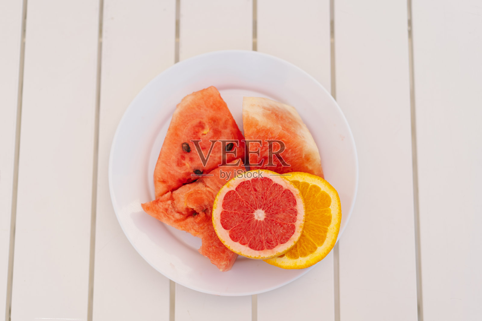 白色盘子里的西瓜和柑橘类水果切片照片摄影图片