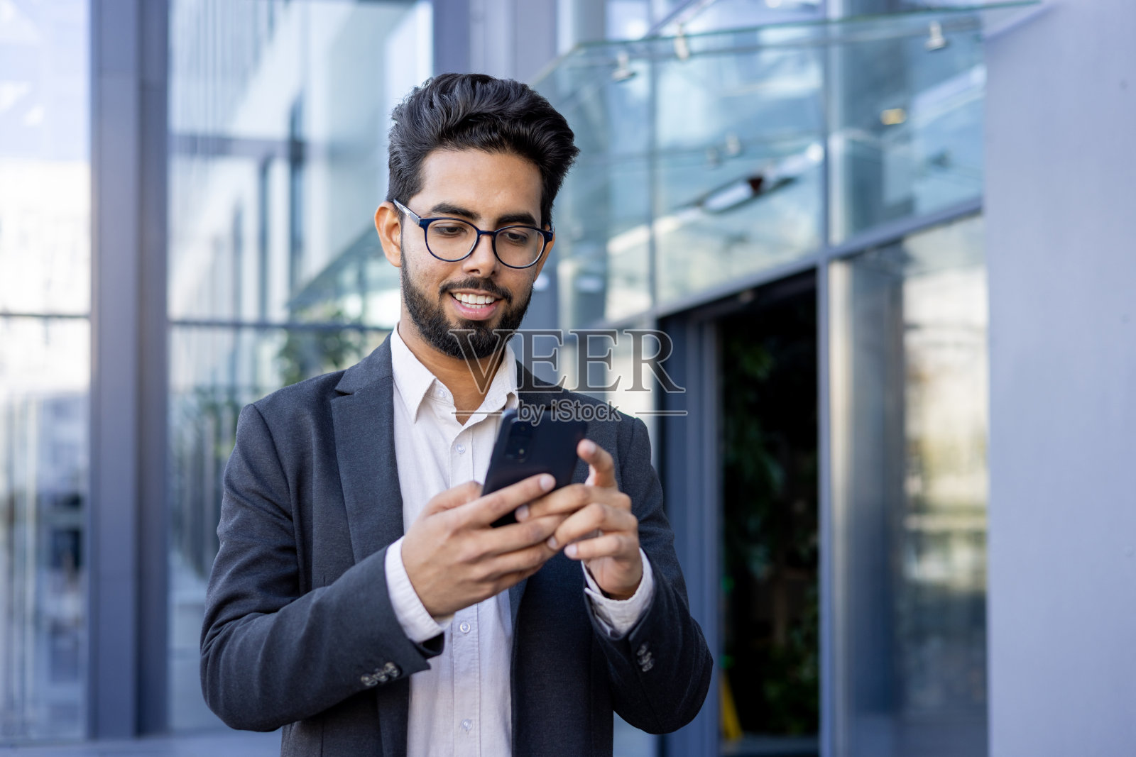 年轻的印度职业男子在城市环境中使用智能手机照片摄影图片