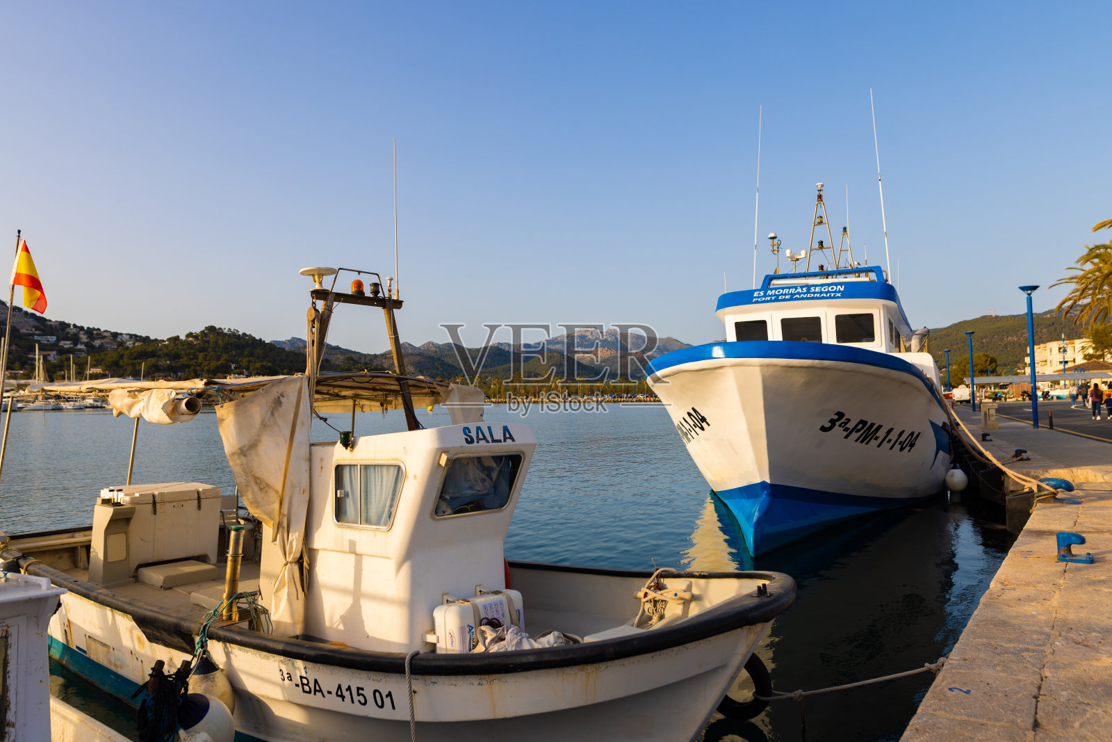 夕阳下，安德拉克斯港的一艘老渔船和一艘游船照片摄影图片