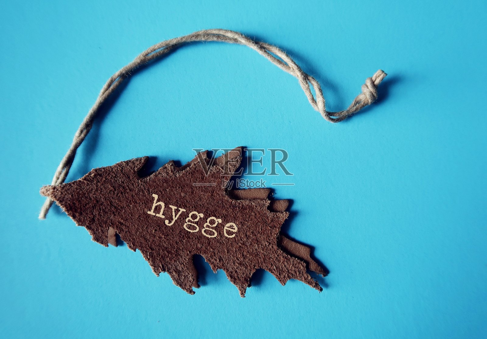 蓝色背景上的皮革标签，文字HYGGE，意为丹麦挪威舒适的生活方式照片摄影图片