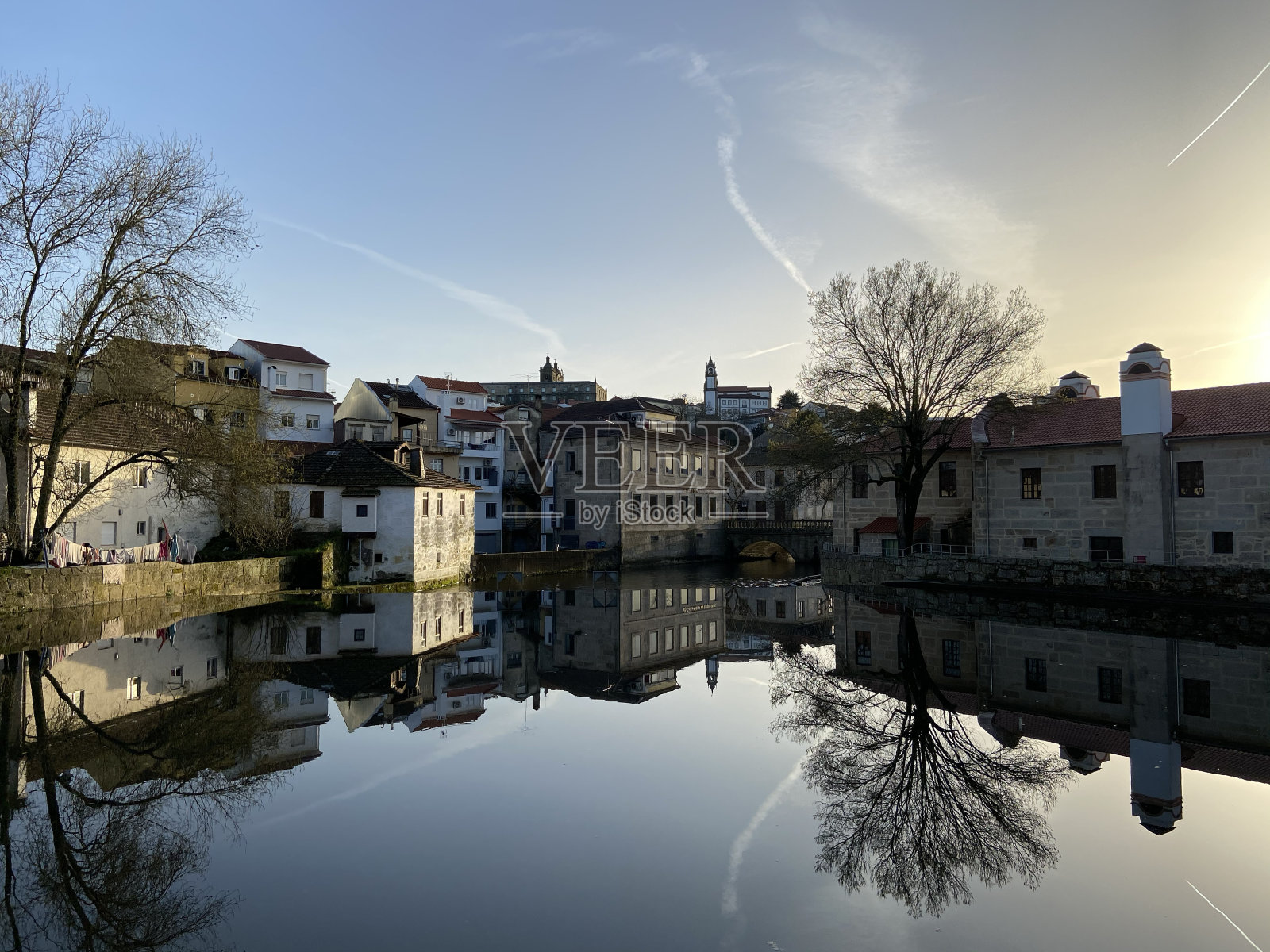 在一个有建筑、树木和水的城市里，太阳正在落下照片摄影图片