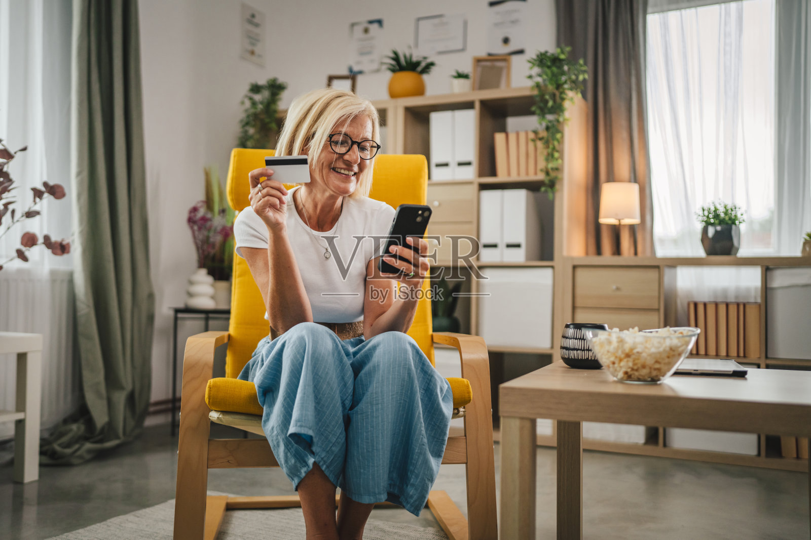成熟的老年女性在家里用信用卡和手机网购照片摄影图片
