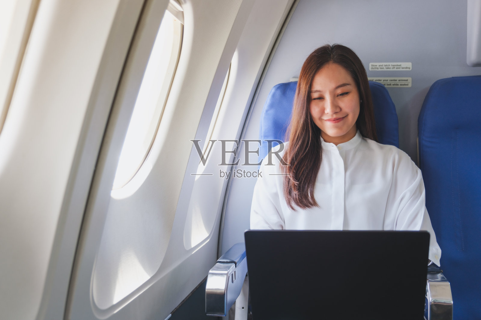 一名妇女在飞机旅行时在笔记本电脑上工作的肖像照片摄影图片