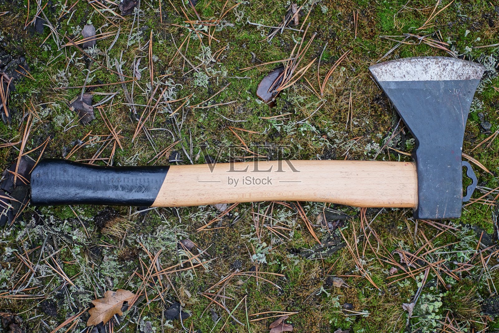 一把带有棕色木柄的黑色斧头躺在地上照片摄影图片