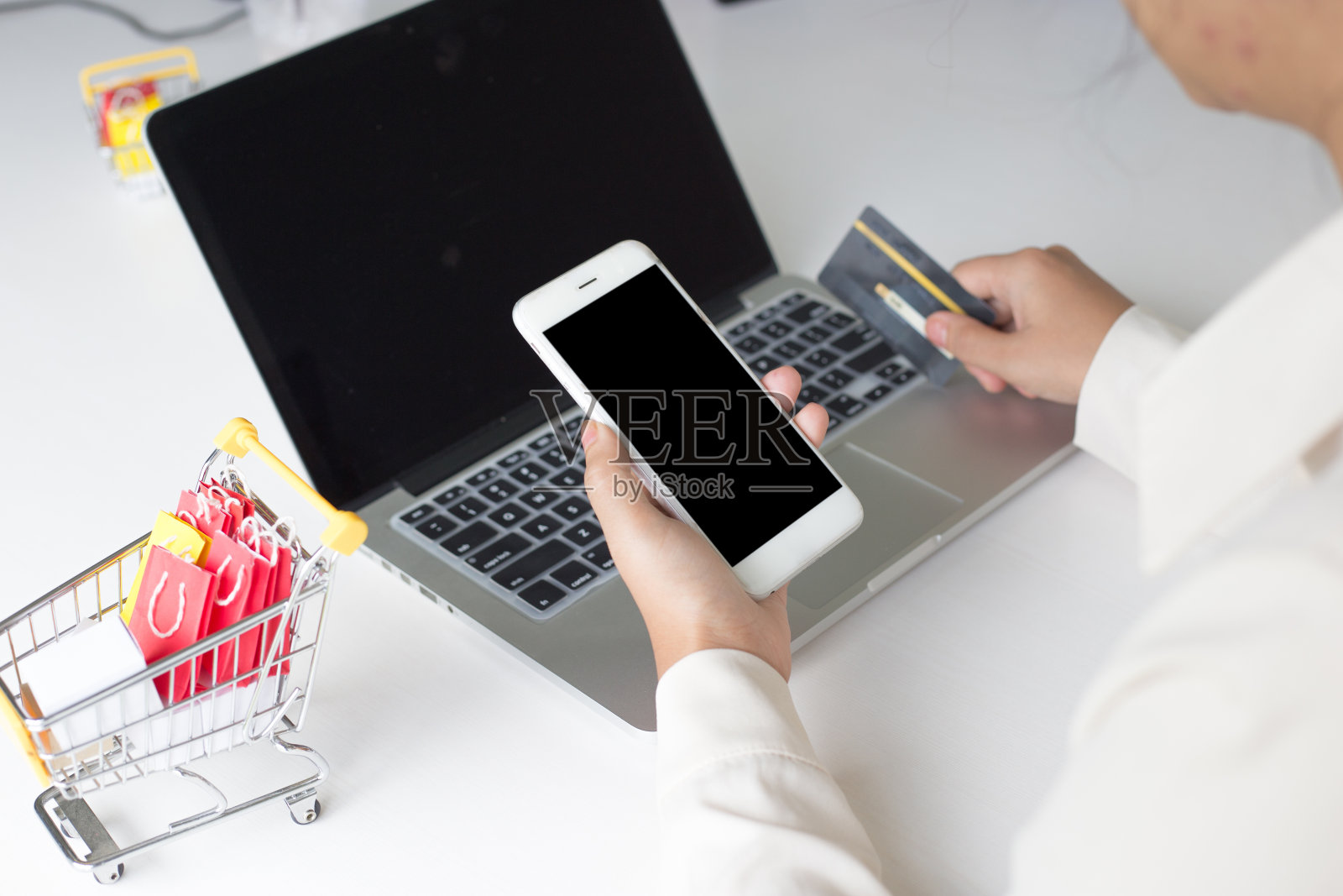 裁剪图像的女人持有信用卡和使用电话在桌子上照片摄影图片