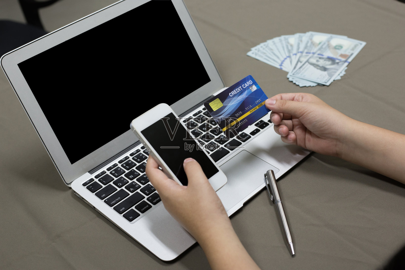 在餐桌上使用笔记本电脑时握着信用卡的女人的双手被剪断照片摄影图片