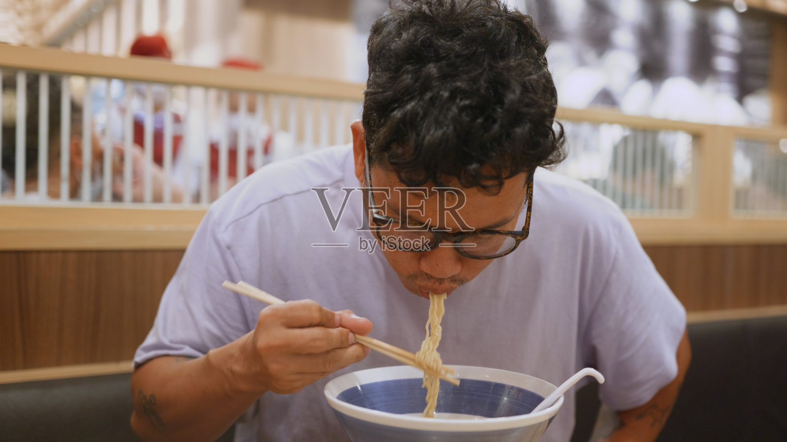 亚洲男子用筷子吃拉面。照片摄影图片