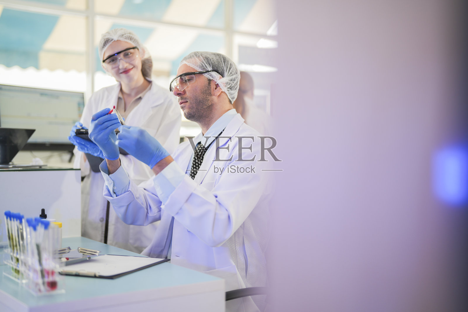 科学家进行实验并记录数据。人们为生产药物和生物化学而安排试管和化学品设备。人们拿着装有化学液体和植物样品的管子。照片摄影图片