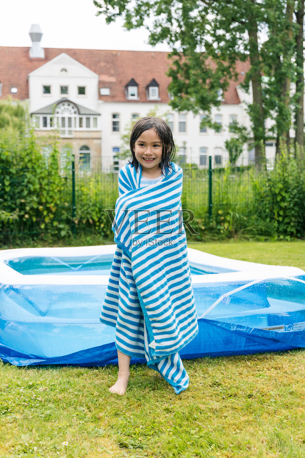 小女孩裹着毛巾站在游泳池旁边，被冻住了照片摄影图片