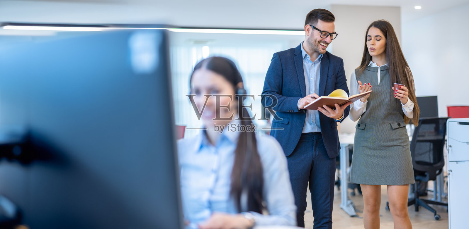 穿着优雅正装的同事在办公室里讨论业务。照片摄影图片