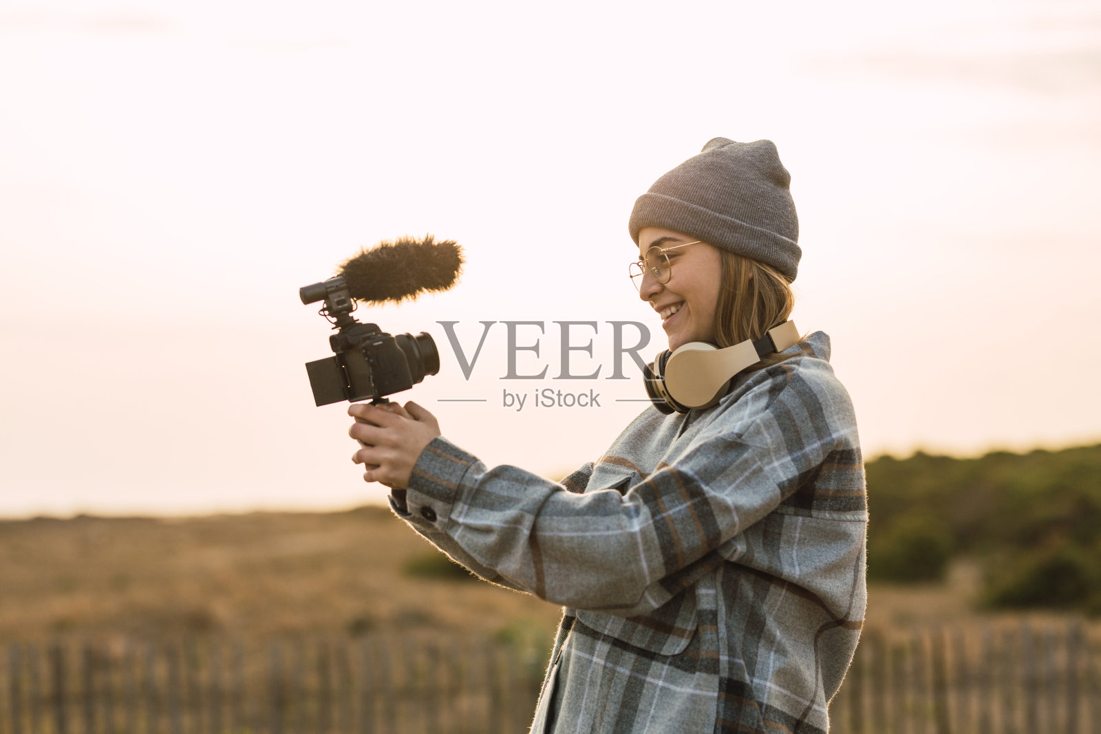 快乐的女士在夕阳下用相机记录视频照片摄影图片