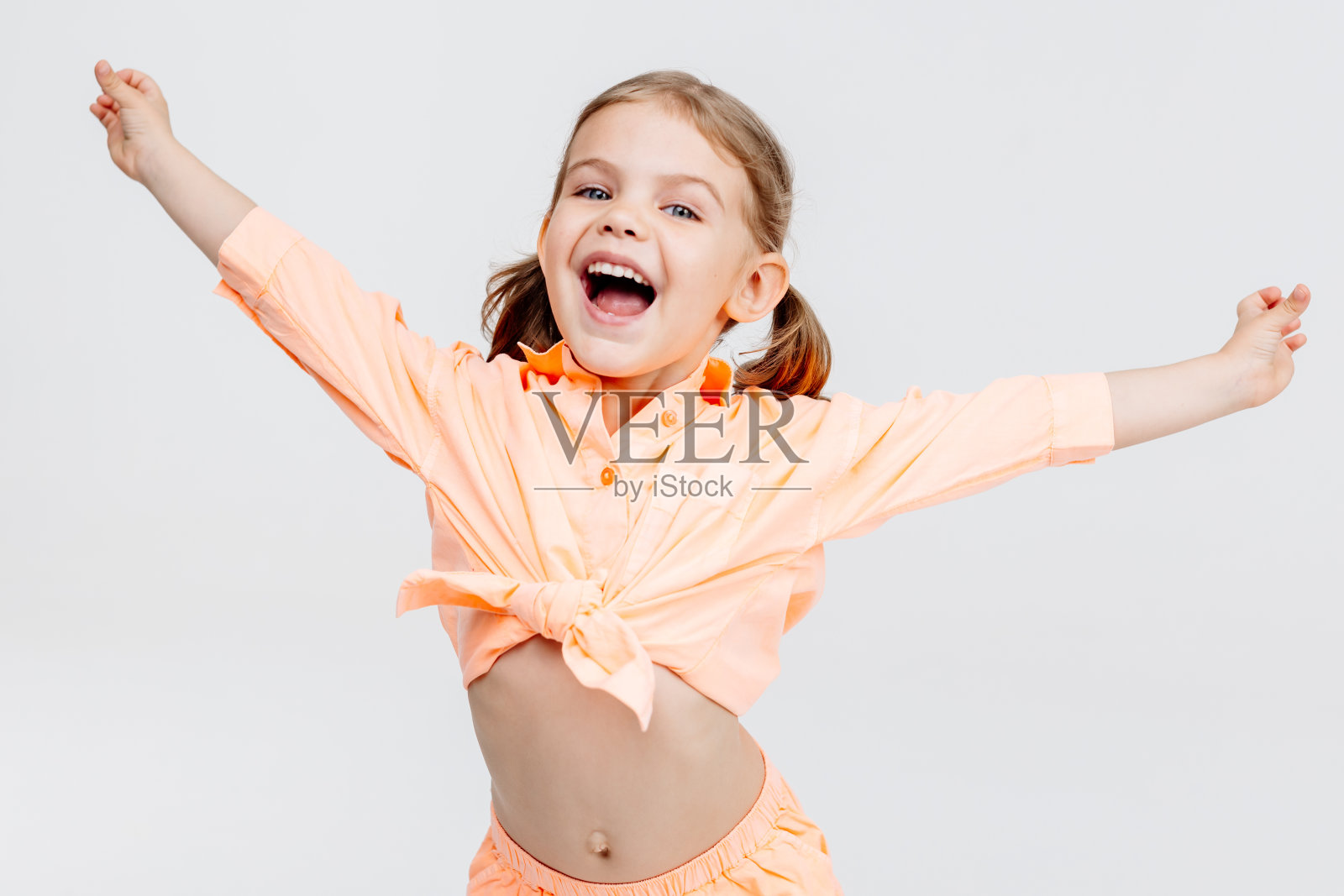 一个穿着时髦的小女孩，在白色的背景上跳舞，玩得很开心。时尚、时尚、有趣的理念。照片摄影图片