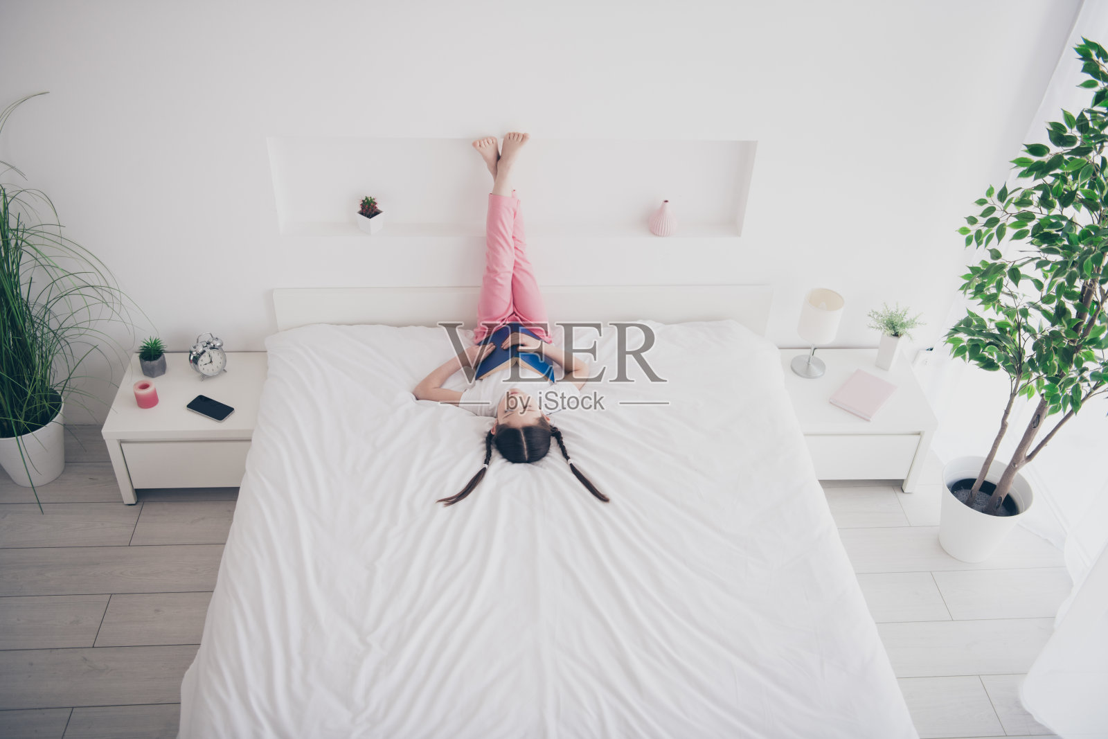 全身高角度看可爱小女孩肖像睡觉拿书穿睡衣舒适的床卧室公寓室内照片摄影图片