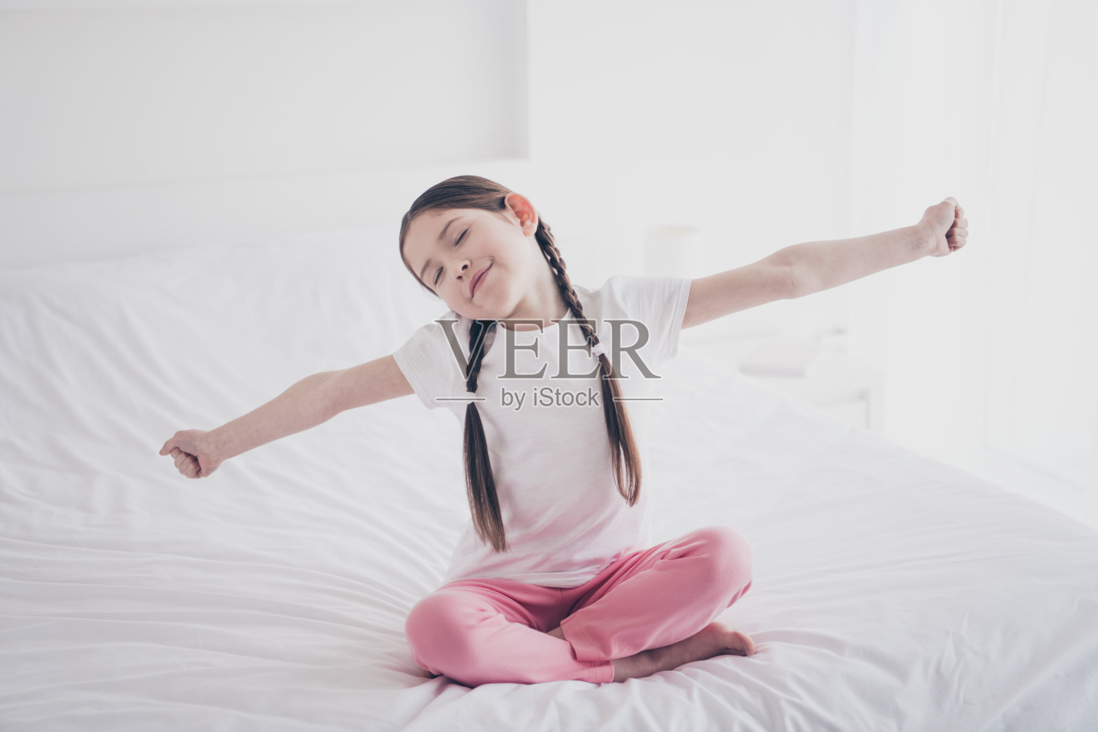 可爱小女孩的全身肖像伸展手臂穿睡衣舒适的卧室公寓室内照片摄影图片