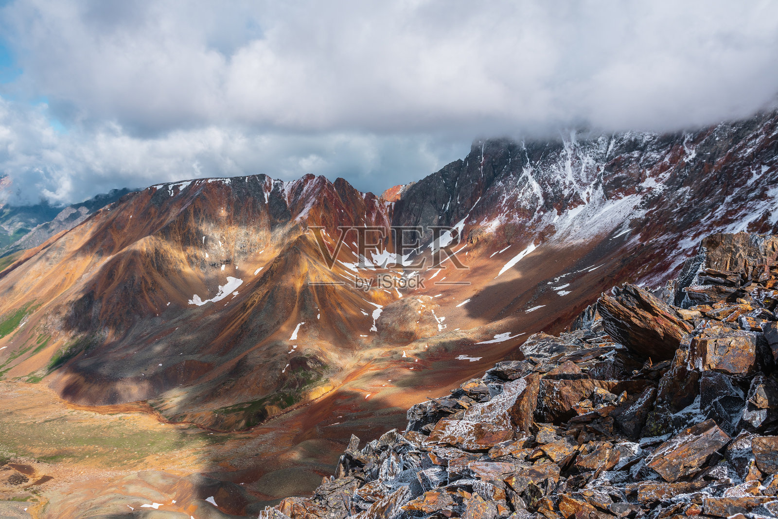 从白雪皑皑的石质深渊边缘到多色山谷，铁河和红色的大岩石山脊。五颜六色的大岩石山。刚下过雪的岩石。生动的高山风光。照片摄影图片