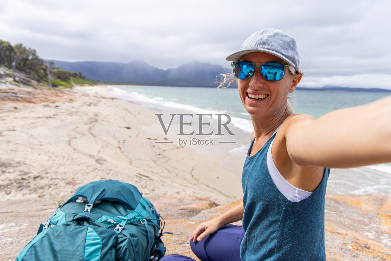 微笑的女人在海滩徒步旅行时自拍照片摄影图片