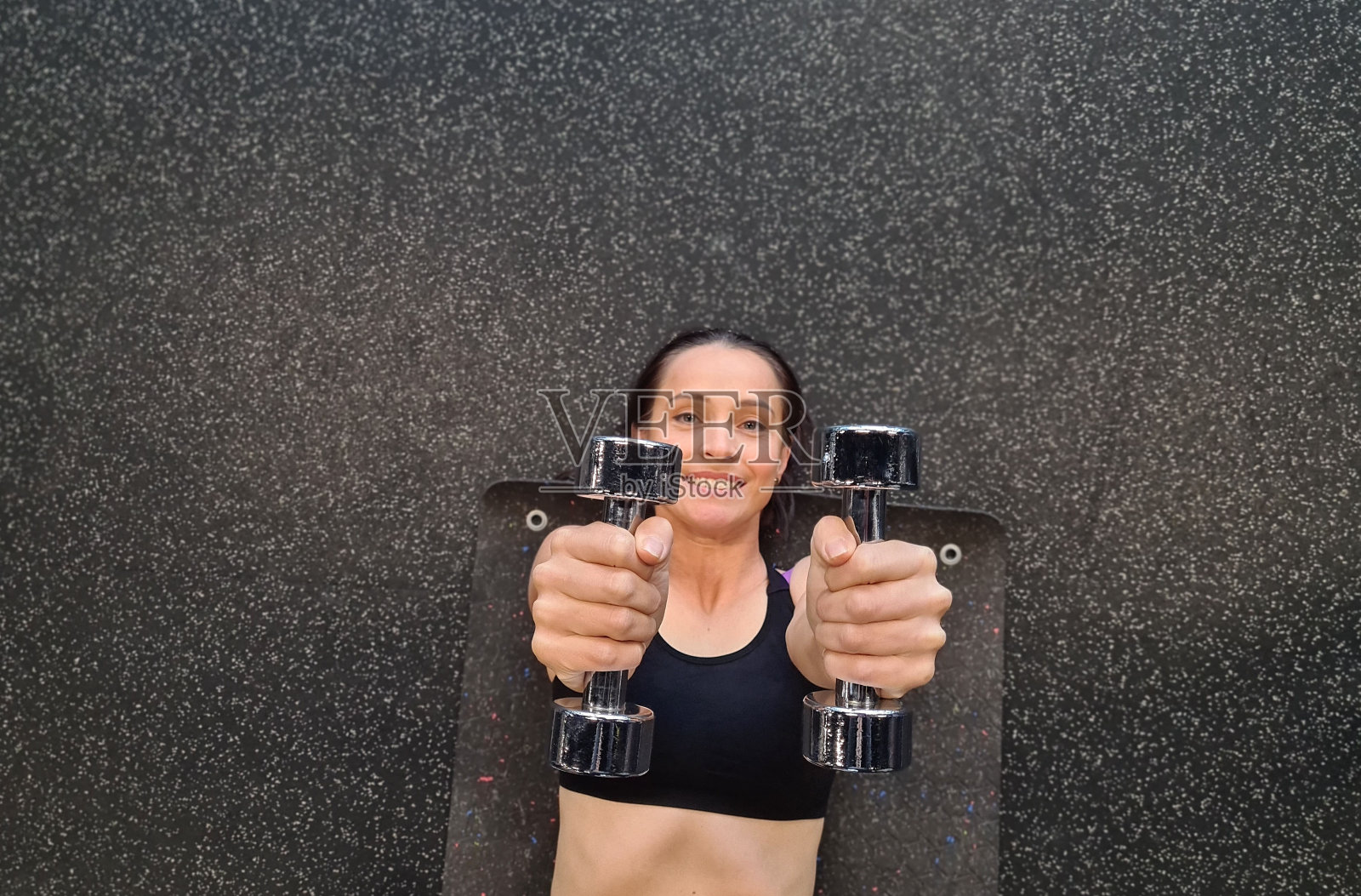 女子在健身房锻炼时手持哑铃照片摄影图片