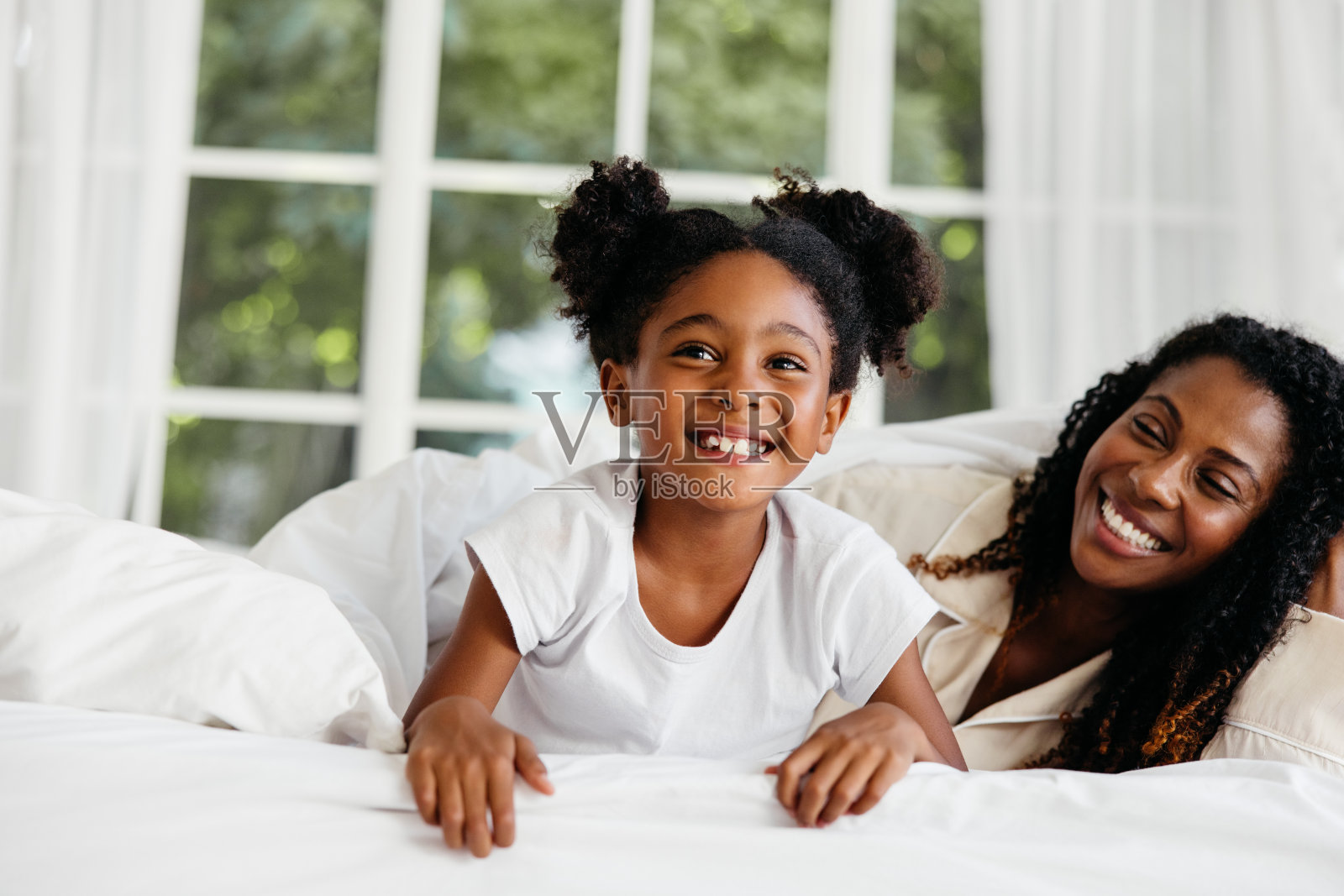 快乐的母亲和女儿在床上享受时光照片摄影图片