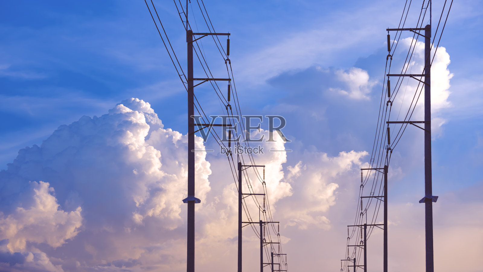 剪影两排电线杆和电缆线对大白色多云的蓝天背景，低角度与复制空间照片摄影图片