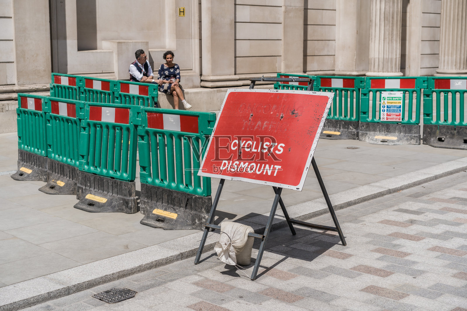 绿色路障前的自行车下马标志，背景中有行人照片摄影图片