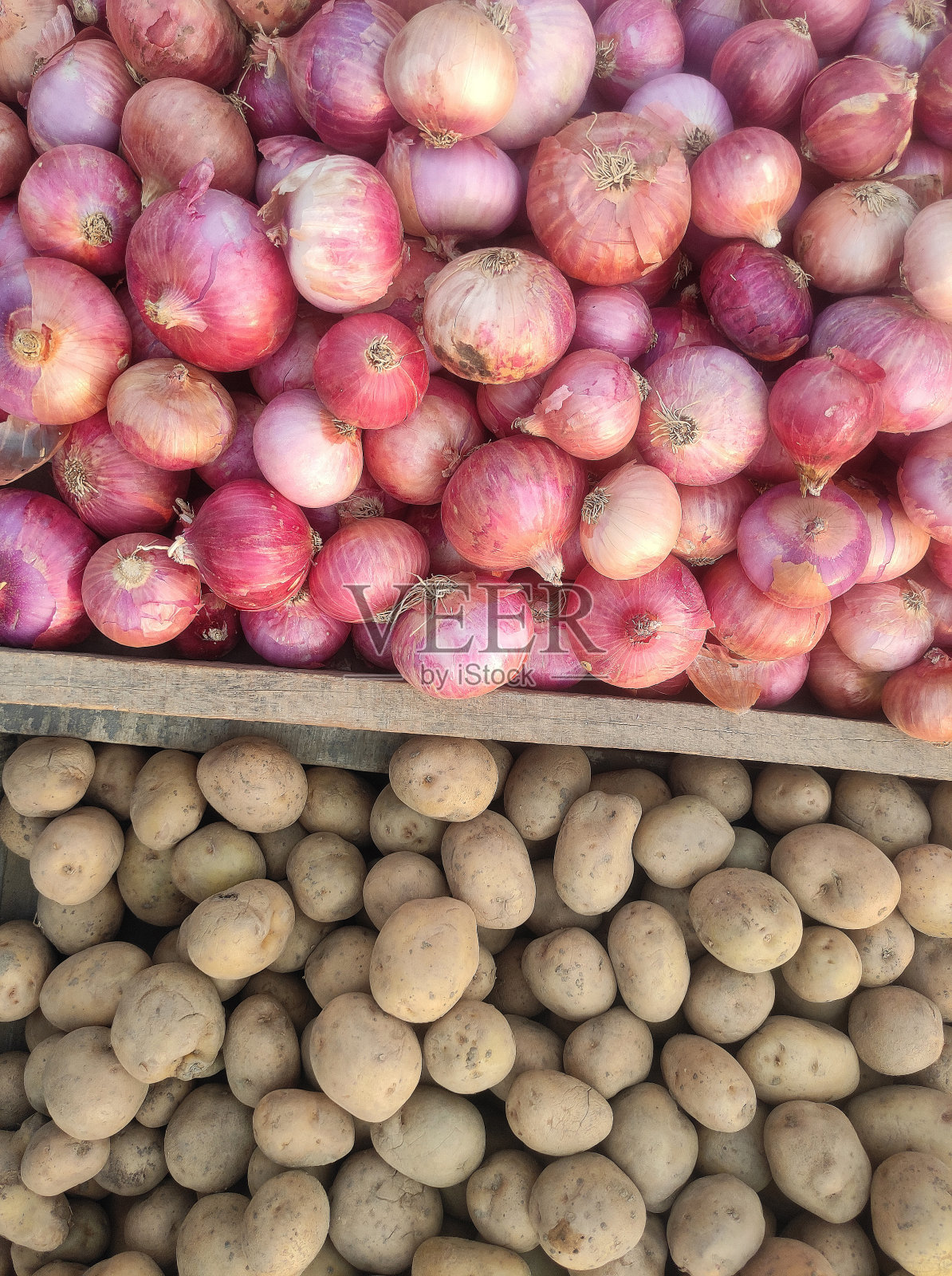 许多aaloo pyaaz或土豆和洋葱蔬菜堆的垂直图像，在农贸市场分开出售，制作海报或食品背景，表示健康的素食主食，由木制框架分开或分割照片摄影图片