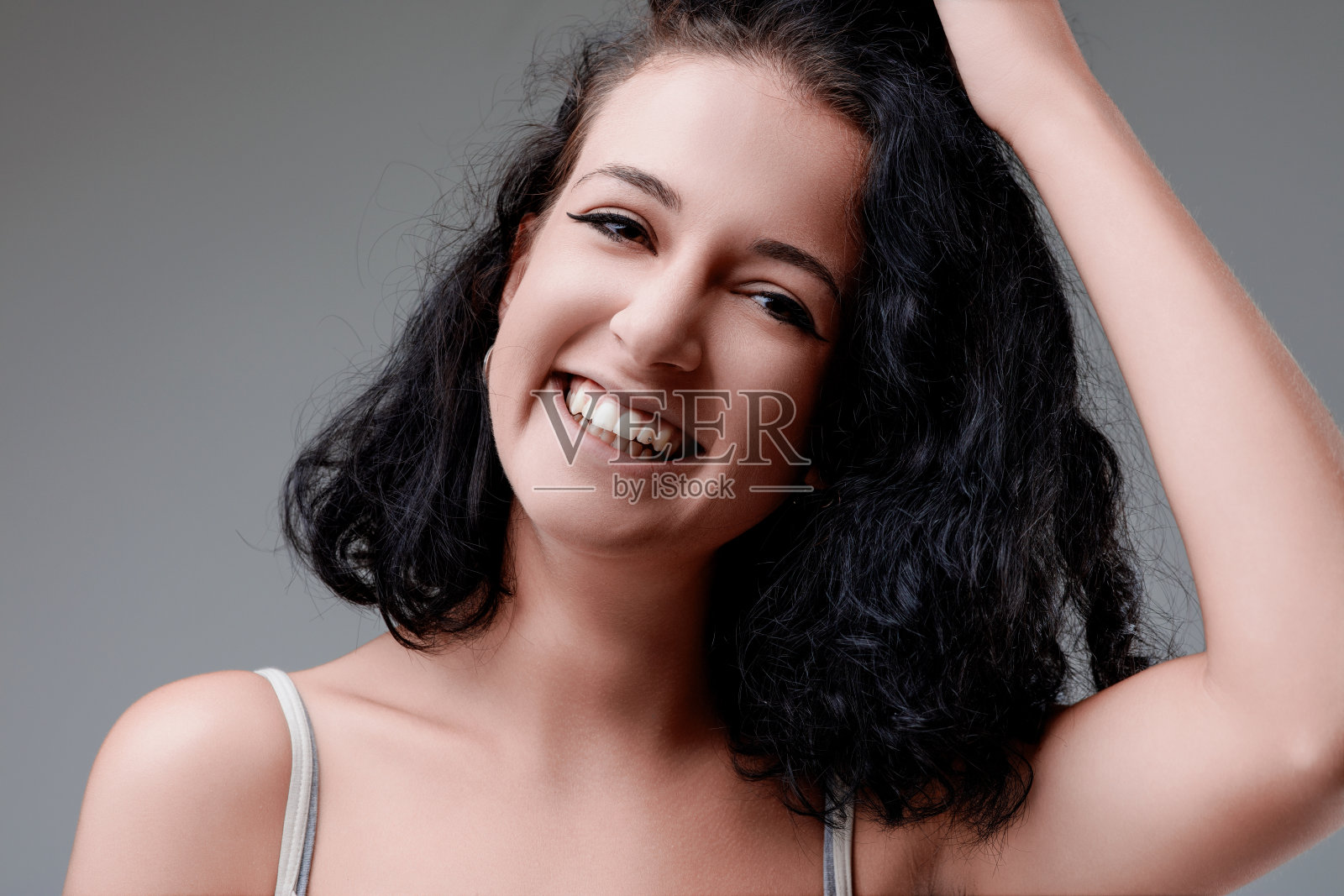 美丽的年轻女子抚摸着她的头发，微笑着照片摄影图片