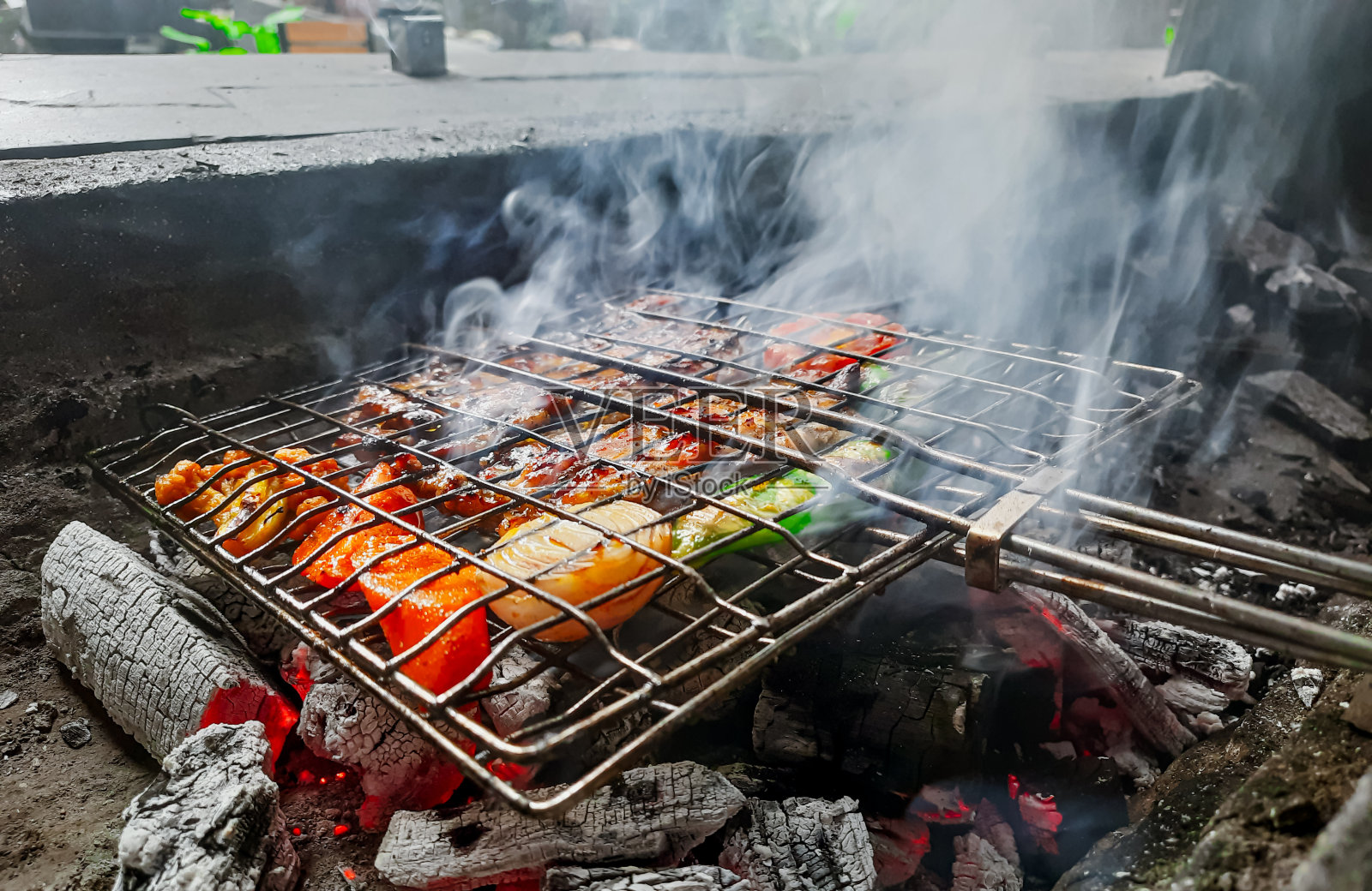 什锦美味的烤肉架上的烟雾和火焰。烤肉串在燃烧的烤架上把肉串和蔬菜串在一起。照片摄影图片