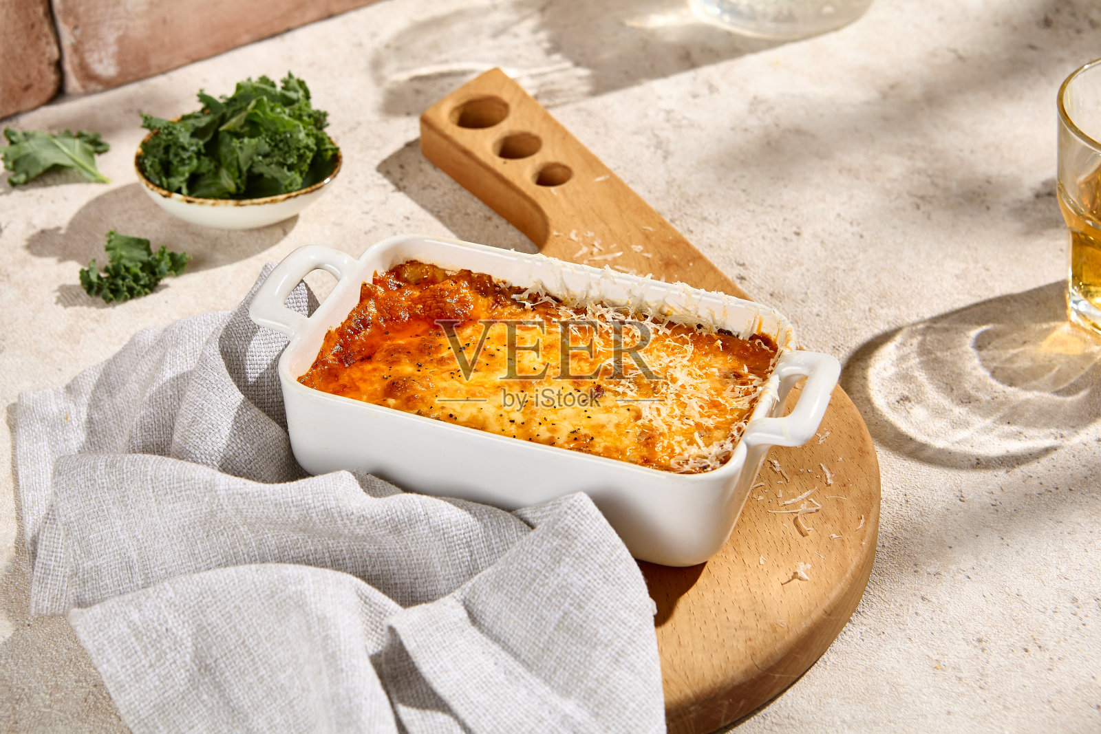 正宗的千层面在陶瓷盘子上自然米色表与阳光和阴影-美学静物照片摄影图片