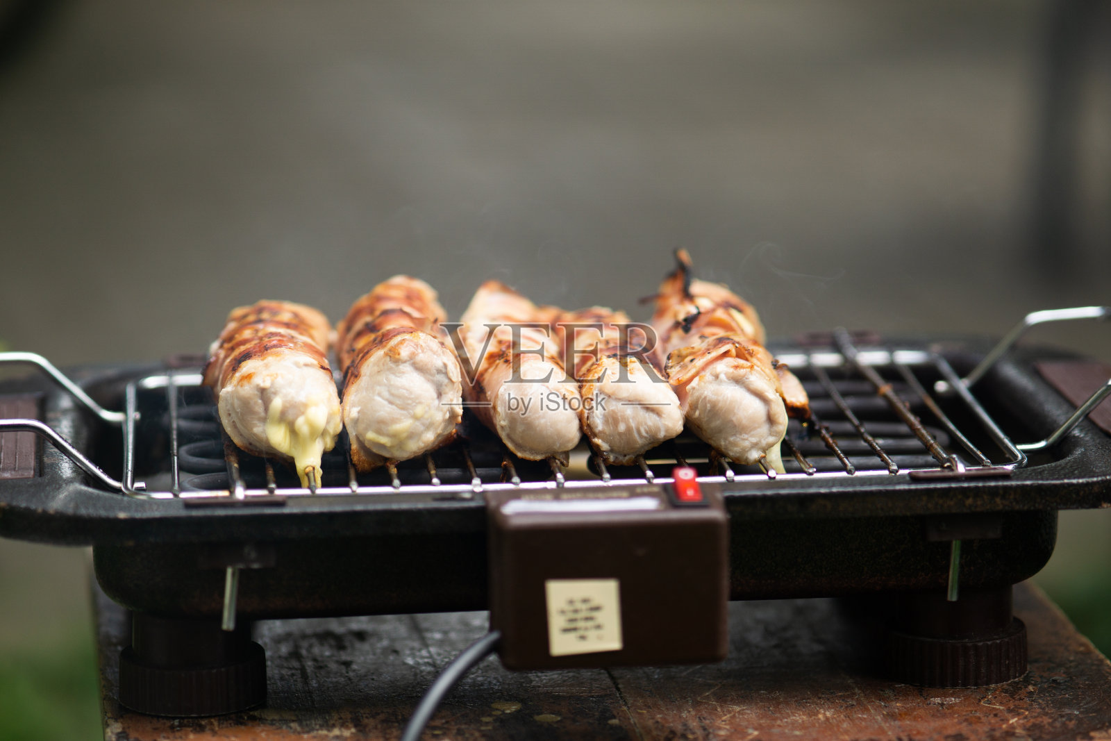 在后院烧烤架上烧烤美味的肉，绿草为背景，烧烤花园烧烤着美味的肉，特写镜头。烤架冒烟照片摄影图片