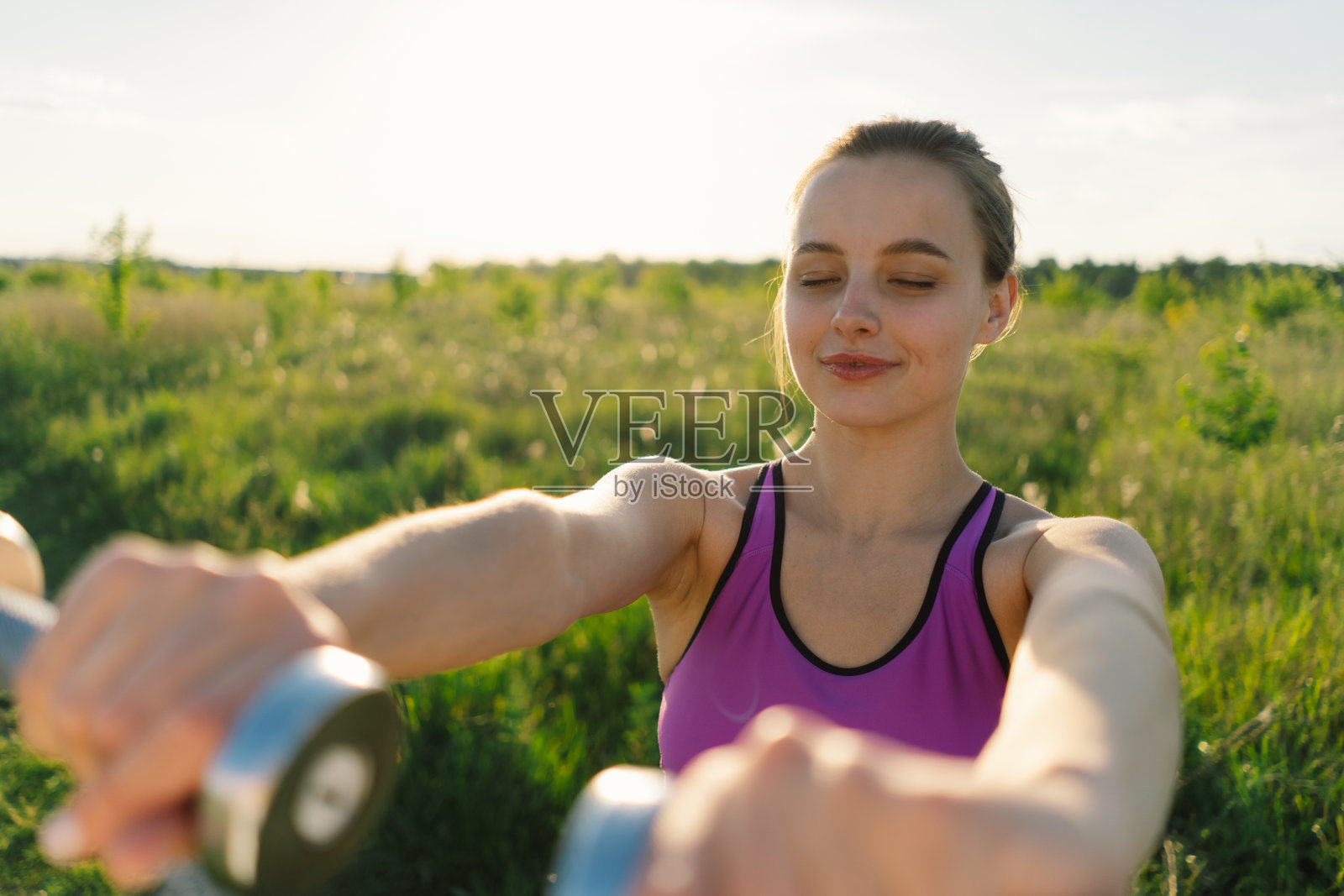 一个女孩在阳光明媚的夏日夕阳下在大自然中健身或做瑜伽照片摄影图片
