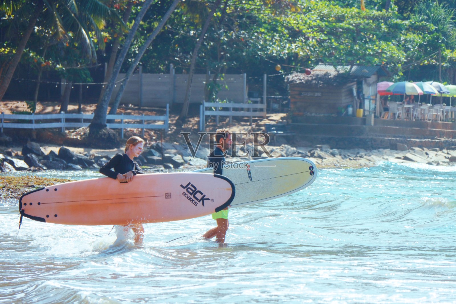 一对冲浪者在热带海滩上扛着冲浪板走进大海照片摄影图片