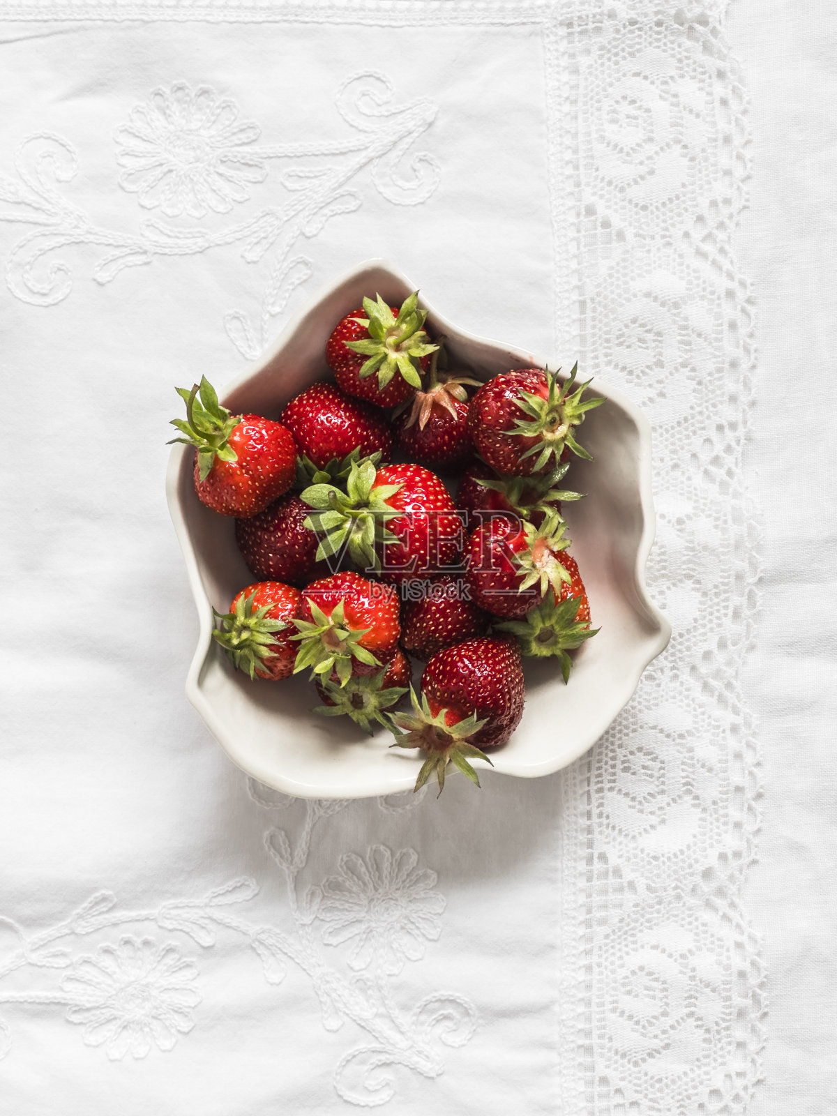 新鲜成熟的草莓在一个陶瓷碗在浅色背景，俯视图照片摄影图片