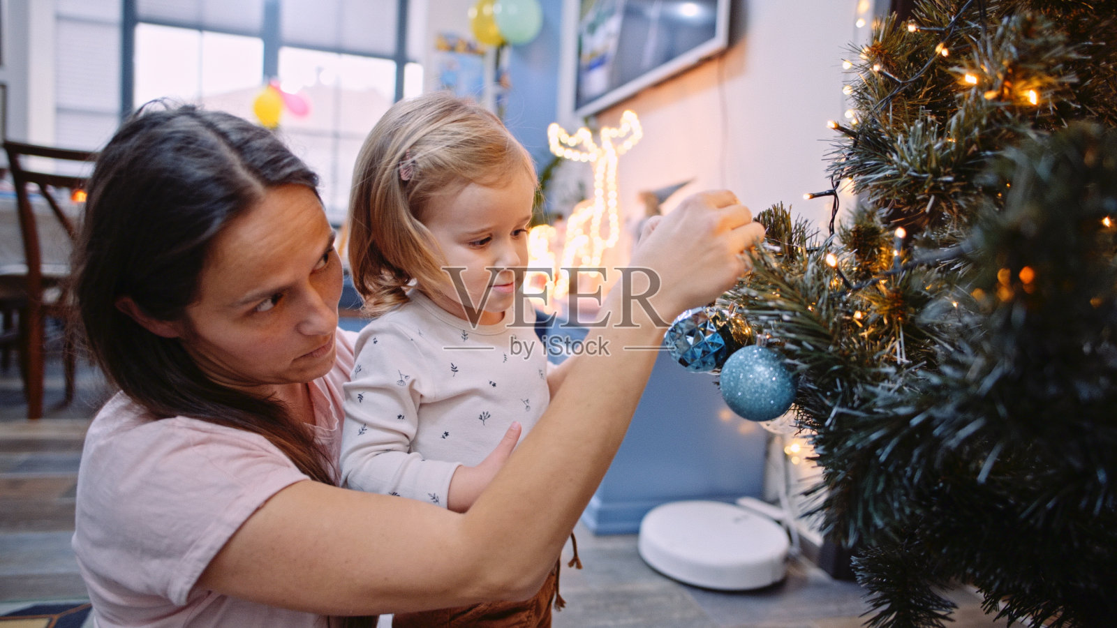 妈妈和孩子在家里装饰圣诞树。照片摄影图片