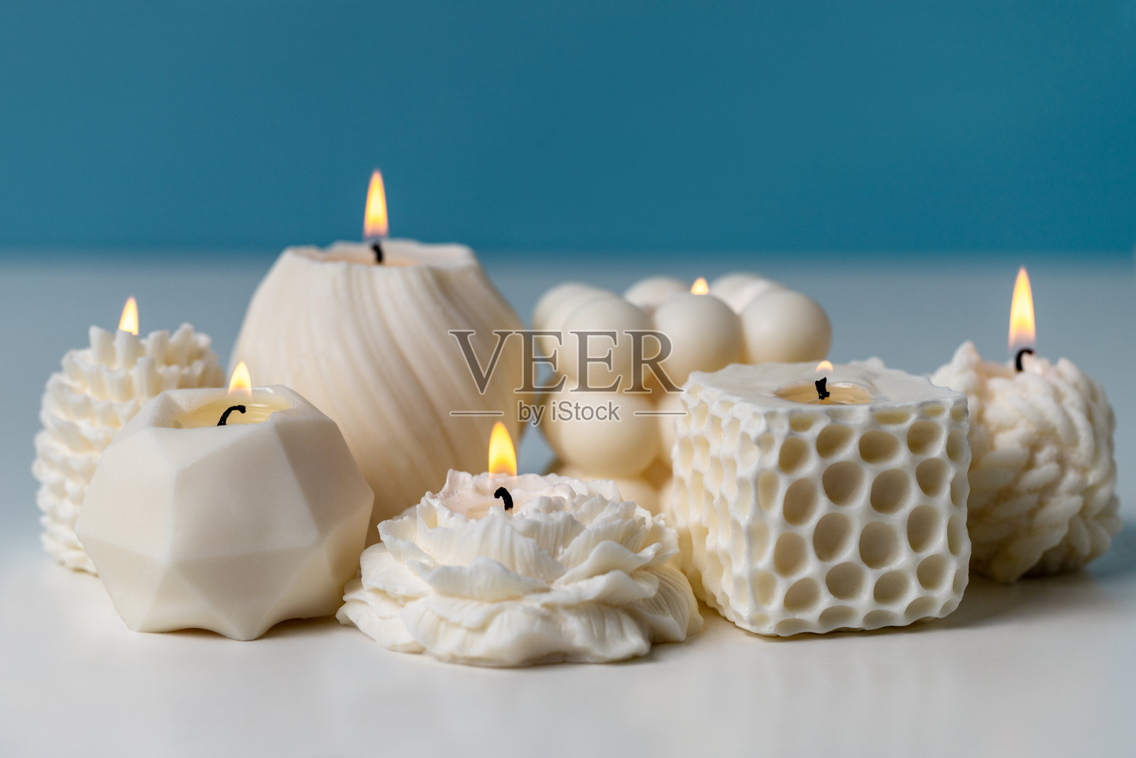 在蓝色的背景下，在白色的桌子上给手工蜡烛打蜡。白色自然香味蜡烛照片摄影图片