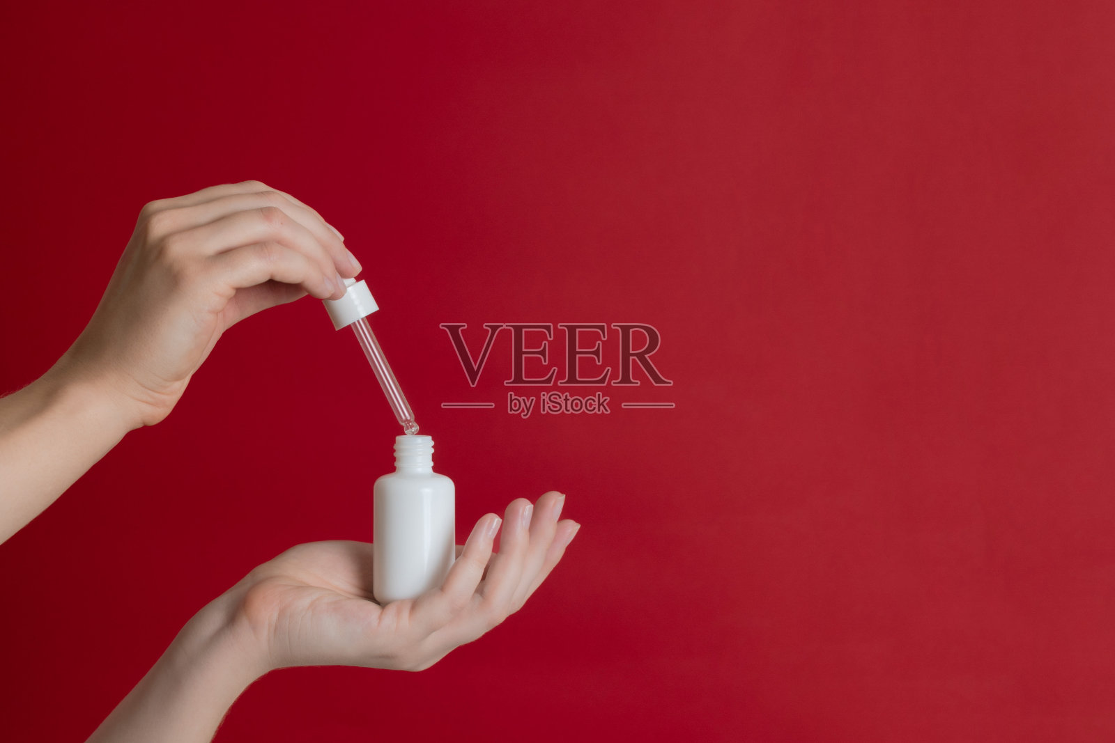 血清玻璃无品牌瓶(精油)与移液管在红色背景。天然保湿，滋养化妆品的皮肤，美容和水疗照片摄影图片