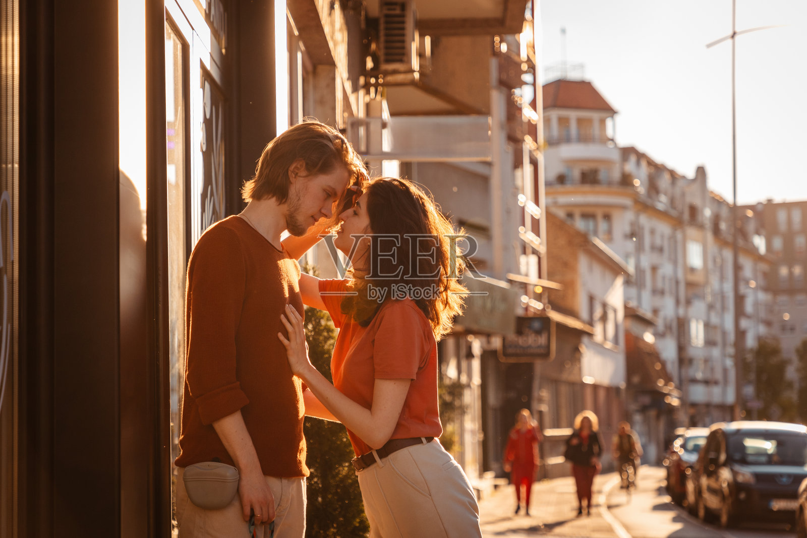 一对年轻的白人男女在街上。背景中的夕阳城照片摄影图片