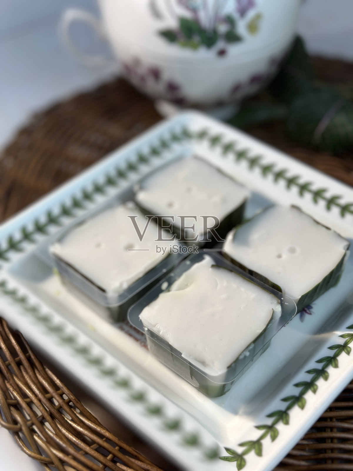 传统的马来西亚蛋糕，被称为Kuih Tepung Pelita或Kuih Sampan在盘子上的深色背景。它是由椰奶和米粉制成的，用香蕉叶调制而成。在斋戒月流行。照片摄影图片