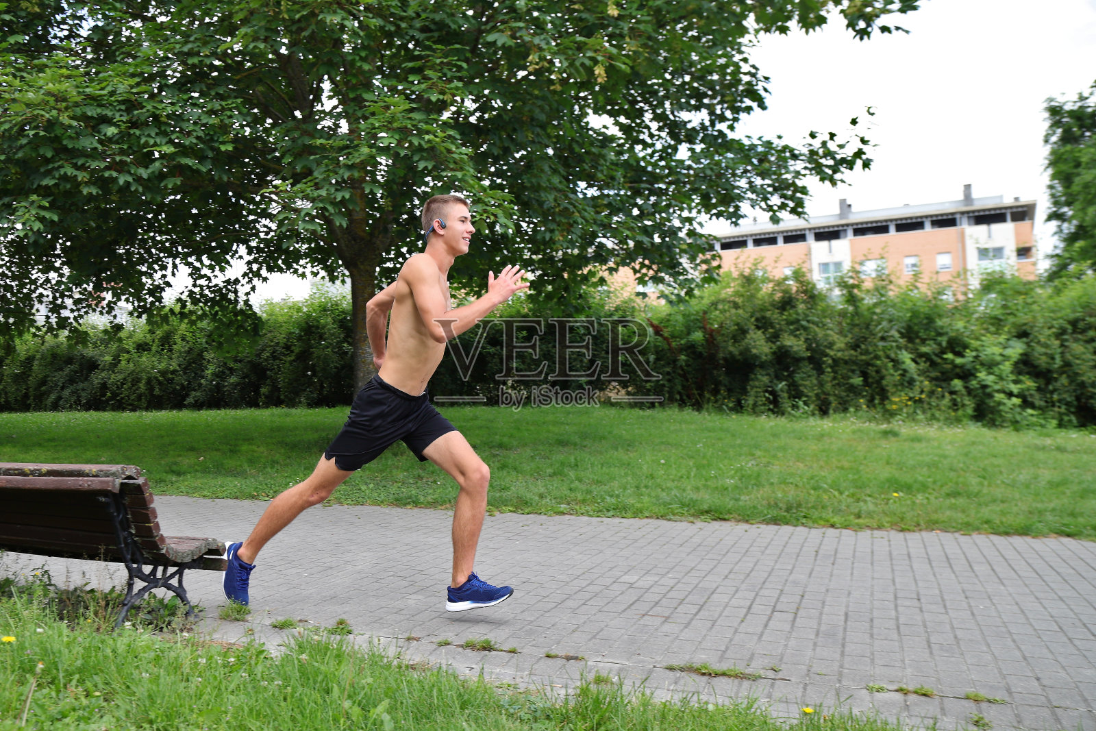 在城市公园跑步的年轻人，戴着耳机慢跑的青少年，在运动照片摄影图片