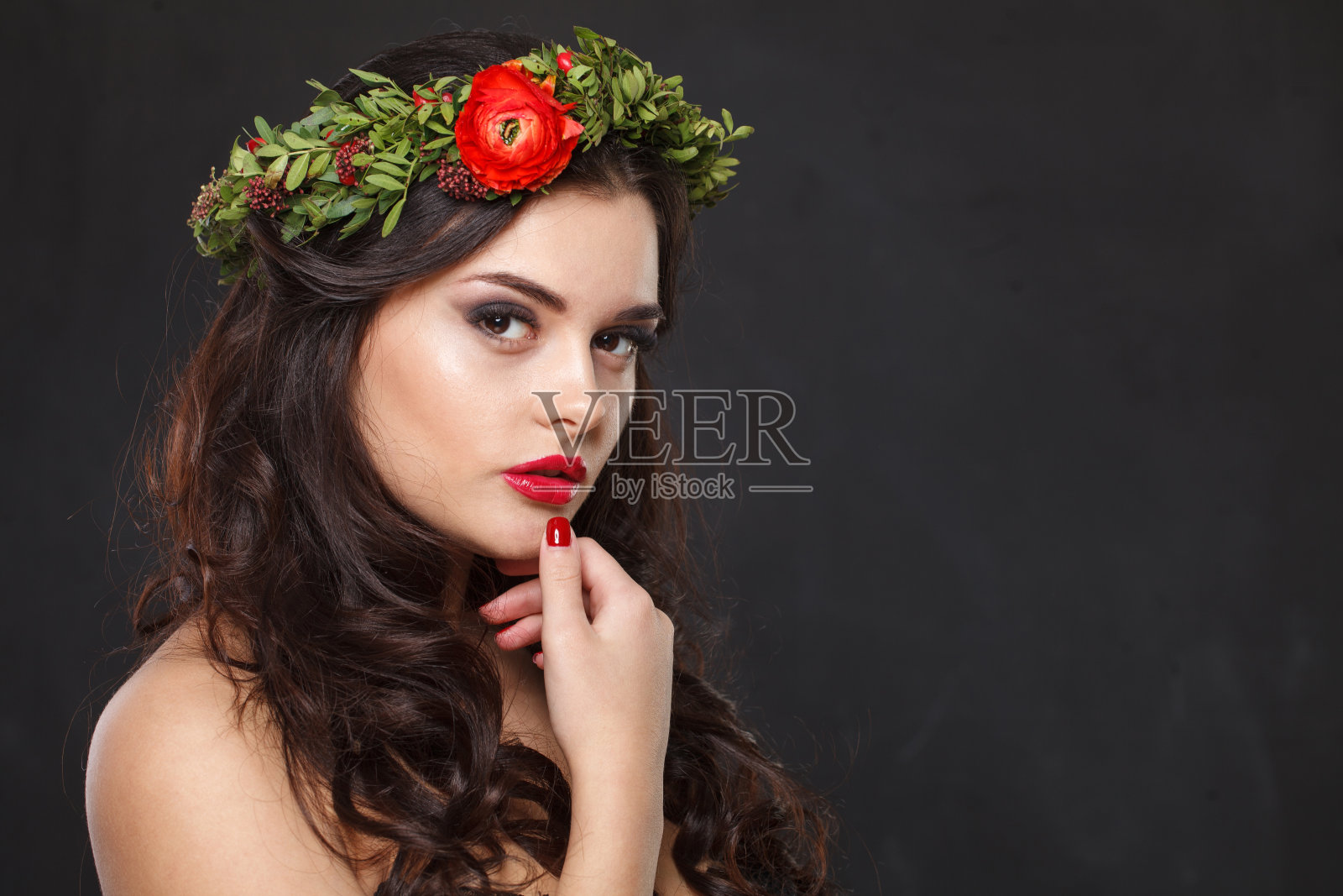 快乐的年轻女子与花头花环看着相机，而站在黑色背景照片摄影图片